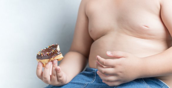 Übergewichtiger Jugendlicher mit Donut in der Hand