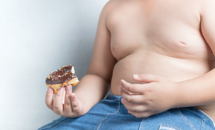 Übergewichtiger Jugendlicher mit Donut in der Hand