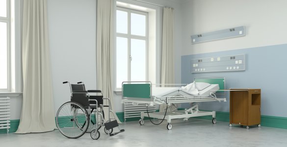 Leeres Krankenzimmer mit Bett und Rollstuhl im Pflegeheim